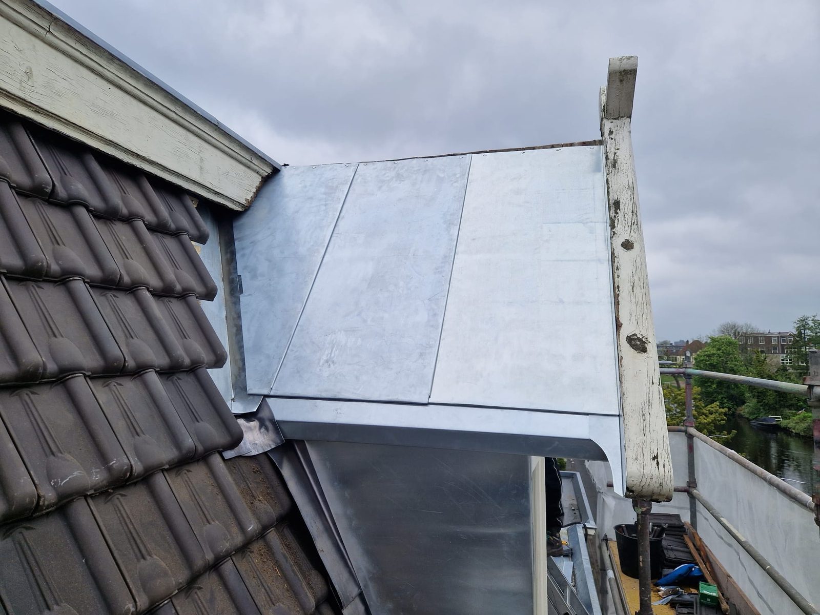 Nieuwe zinken dakgoot langs pannendak